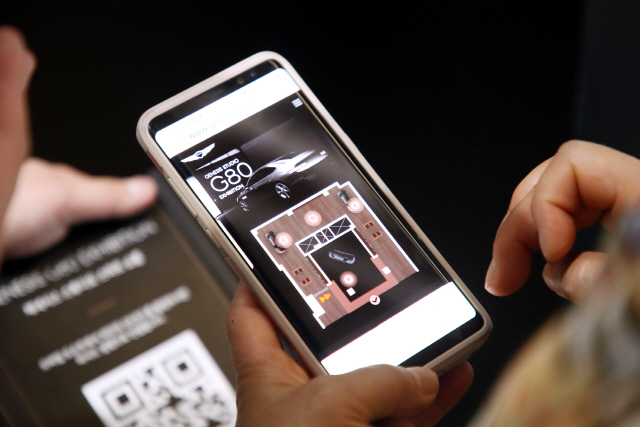 제네시스 스튜디오 하남을 방문한 고객이 개인 스마트폰을 통해 신형 G80의 설명을 볼 수 있는 모바일 도슨트 서비스를 이용하고 있다./사진제공=현대차