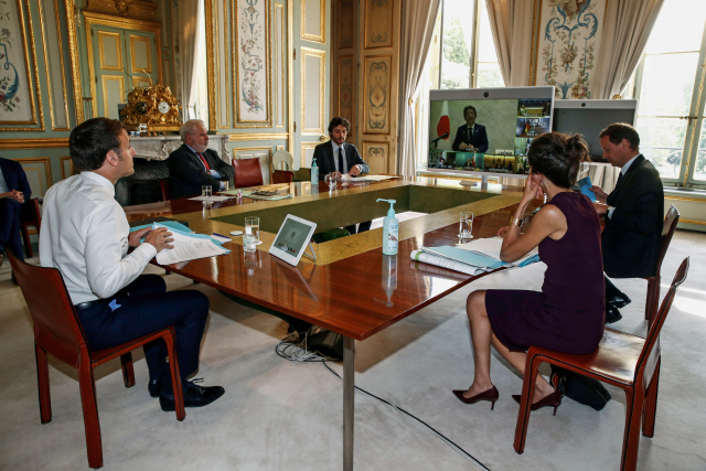 에마뉘엘 마크롱(왼쪽) 프랑스 대통령이 16일(현지시간) 파리 엘리제궁에서 모니터 화면을 통해 주요7개국(G7) 정상들과 코로나19 대응 관련 화상회의를 하고 있다. /파리=AFP연합뉴스