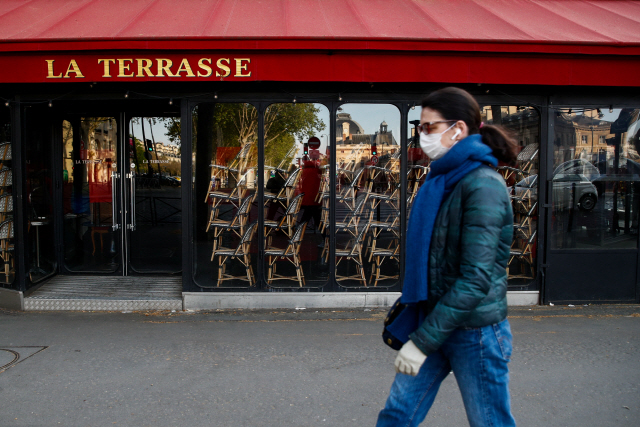 지난 16일(현지시간) 신종 코로나바이러스 감염증(코로나19)으로 영업을 하지 않는 프랑스 파리의 한 식당 앞을 마스크를 쓴 행인이 지나가고 있다./파리=로이터연합뉴스