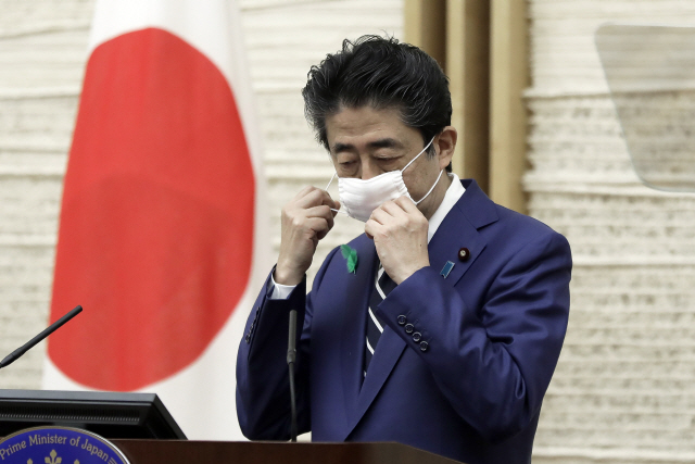 아베 신조 일본 총리가 17일 도쿄 총리관저에서 신종 코로나바이러스 감염증(코로나19) 관련 기자회견을 시작하기 앞서 마스크를 벗고 있다. /도쿄=AP연합뉴스
