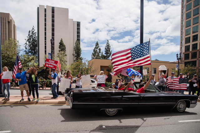18일(현지시간) 미국 캘리포니아주 샌디에이고에서 코로나19로 인한 봉쇄령의 해제를 요구하는 주민들이 성조기와 푯말을 들고 시위를 벌이고 있다.  　 /샌디에이고=AFP연합뉴스