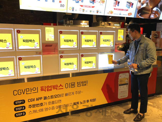 서울 여의도에 위치한 CGV 여의도점에서 한 관객이 픽업박스를 통해 직원과 대면 없이 주문한 팝콘을 수령하고 있다. CGV는 코로나19 사태를 계기로 ‘언택트 서비스’를 강화하겠다고 20일 밝혔다./사진제공=CGV