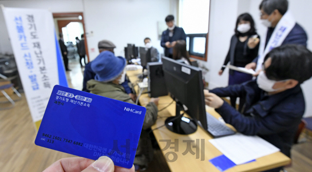 경기도 재난기본소득  오프라인 신청 첫날인 20일 경기 과천시 부림동 주민센터를 찾은 시민들이 선불카드를 신청하고 있다. 경기도 재난기본소득 수령을 위한 선불카드는 도내 545개 읍·면·동 주민자치센터와 216개 농협지점, 725개 지역농축협지점에서 신청할 수 있다. /과천=이호재기자