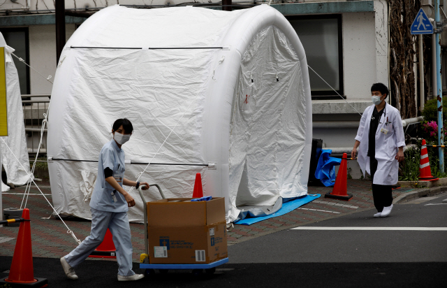 일본 도쿄 카와키타 종합병원 야외에 신종 코로나바이러스 감염증(코로나19) 검사를 위해 설치된 텐트들 옆으로 지난 17일 의료 관계자들이 지나가고 있다. /도쿄=로이터연합뉴스