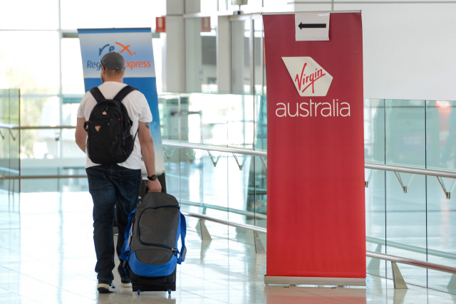 21일(현지시간) 한 여행객이 호주 애들레이드 공항 출국장에서 버진오스트레일리아 사인 앞을 지나고 있다. /애들레이드=AFP연합뉴스