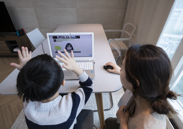 지난 20일 오전 서울 용산구의 한 가정에서 용산초등학교 1학년에 입학한 신입생 어린이가 엄마와 함께 노트북 화면을 통해 온라인 입학식을 갖고 있다. /연합뉴스