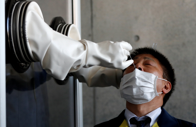 23일 일본 도쿄에서 마스크를 쓴 코로나19 의심환자가 PCR 검사를 받고 있다./도쿄=로이터연합뉴스