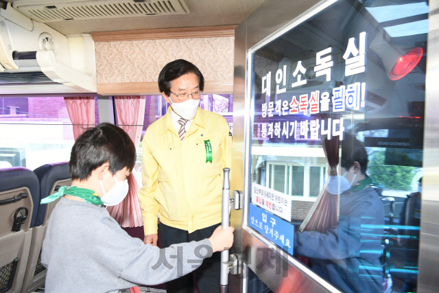 고윤환 문경시장이 대형버스를 개조한 설치한 대인소독기를 이용하는 어린이에게 사용법을 설명하고 있다.