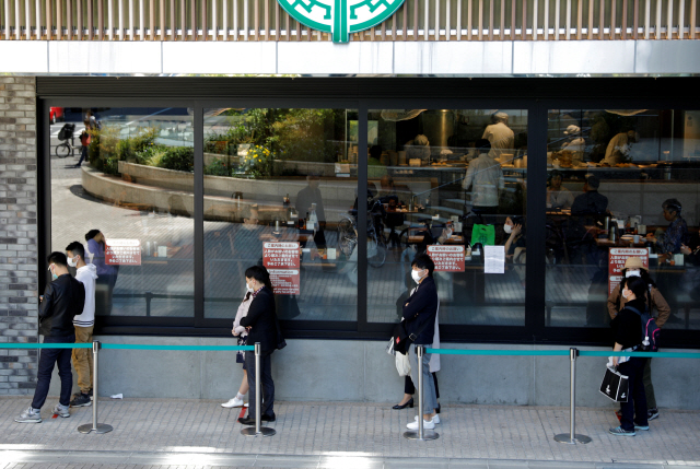 마스크를 착용한 도쿄 시민들이 25일 한 식당 밖에서 일정한 간격으로 떨어져 줄을 서 있다.  /도쿄=로이터연합뉴스