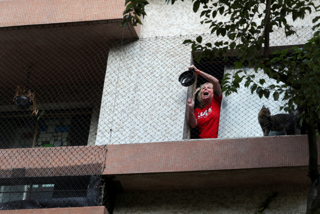 24일(현지시간) 브라질 상파울루에서 한 시민이 세르지우 모루 법무장관의 사임 발표 직후 자신의 집 창문 밖으로 나와 냄비를 두드리며 자이르 보우소나루 대통령의 사퇴를 요구하고 있다./상파울루=로이터연합뉴스