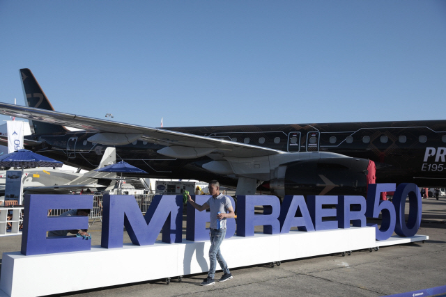 An employee cleans a logo celebrating the 50th anniversary of Embraer SA near an E195-E2 series jet during E195-E2 series jet during the 53rd International Paris Air Show at Le Bourget, in Paris, France, on Monday, June 17, 2019. The show is the world‘s largest aviation and space industry exhibition and runs from June 17-23. Photographer: Jason Alden/Bloomberg