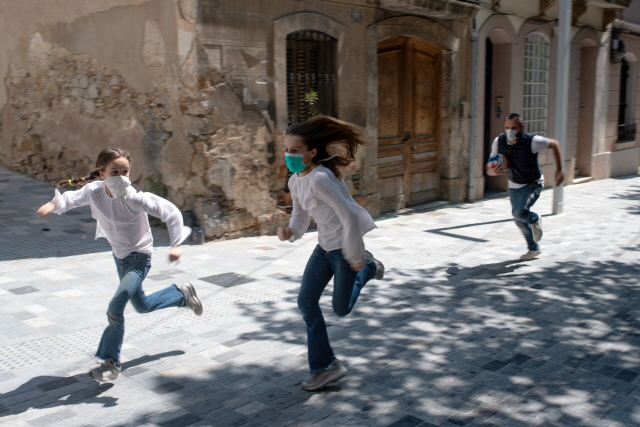 코로나19 확산 억제를 위해 강력한 봉쇄령을 시행해온 스페인에서 6주 만에 어린이의 외출이 허용된 26일(현지시간) 바르셀로나의 한 거리에서 마스크를 쓴 어린이들이 아빠와 함께 뛰어놀고 있다.  /바르셀로나=AFP연합뉴스