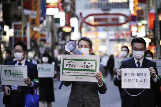 도신종 코로나바이러스 감염증(코로나19) 확산으로 일본 전역에 긴급사태가 선포된 가운데 지난 24일 도쿄의 대표적 유흥가인 신주쿠구 가부키초 거리에서 마스크를 쓴 도쿄도 직원들이 시민들에게 외출 자제를 당부하고 있다. /도쿄=AP연합뉴스