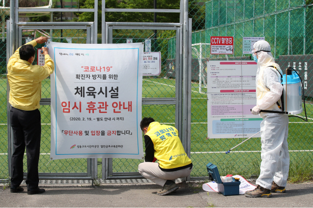 지난 4일 서울 응봉축구장에서 성동구청 관계자들이 경기장 방역을 위해 임시 휴관 안내문을 철거하고 있다./연합뉴스