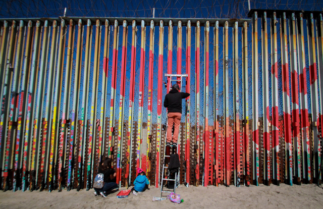 지난 2월 15일 멕시코 북서부 바하칼리포르니아 주의 국경 도시인 티후아나에서 사람들이 미국과 멕시코 국경에 세워진 벽에 색칠을 하고 있다,/EPA연합뉴스