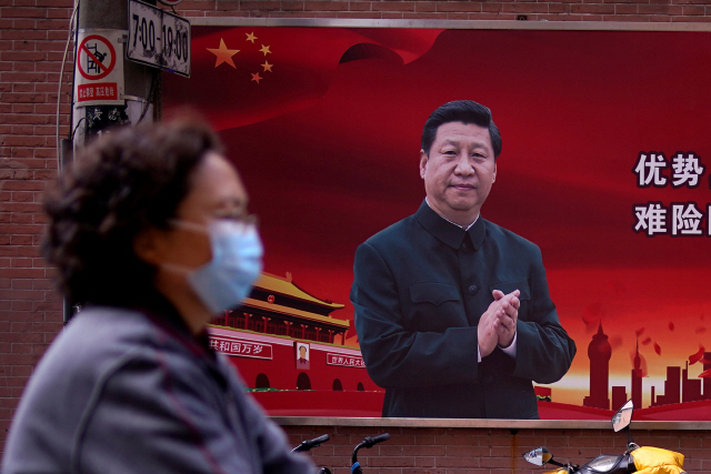중국 상하이에서 한 여성이 시진핑 주석의 초상화 앞을 지나가고 있다. 중국은 먼저 미중합의를 파기하기보다는 미국을 지치게 하는 방향을 택할 가능성이 있다. /로이터연합뉴스