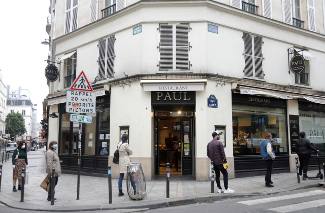 지난 5일(현지시간) 프랑스 파리 시내의 한 빵집 앞에 마스크를 쓴 사람들이 일정한 간격을 유지하며 줄을 지어 서있다./파리=로이터연합뉴스