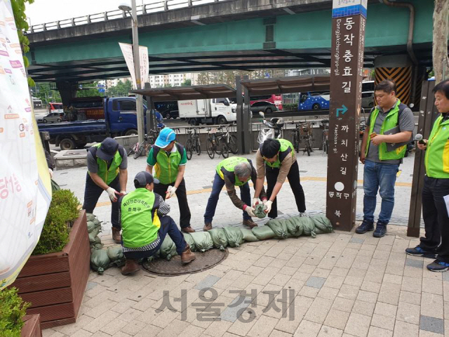 서울 동작구청 관계자들이 지난해 실시된 풍수해 예방훈련에 참가해 도로턱에 모래주머니를 쌓고 있다./사진제공=동작구