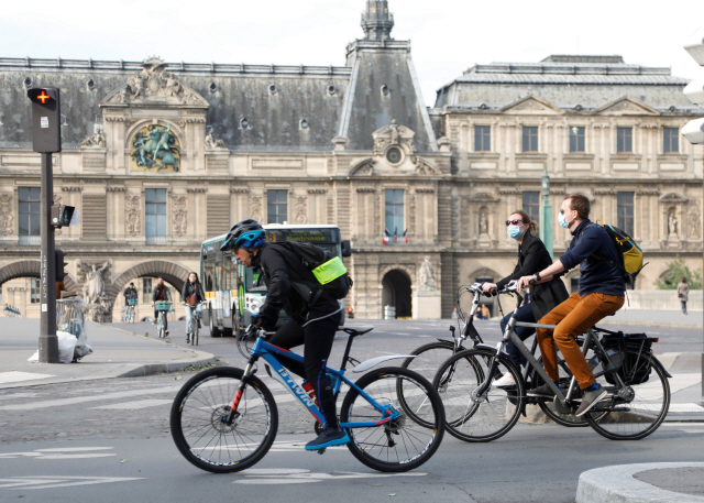 코로나19 확산세가 꺾이면서 프랑스 등 유럽 일부 국가들이 국경봉쇄 조치를 완화하고 있는 가운데 13일(현지시간) 파리 시민들이 자전거를 타고 루브르박물관 앞을 지나가고 있다. /파리=로이터연합뉴스