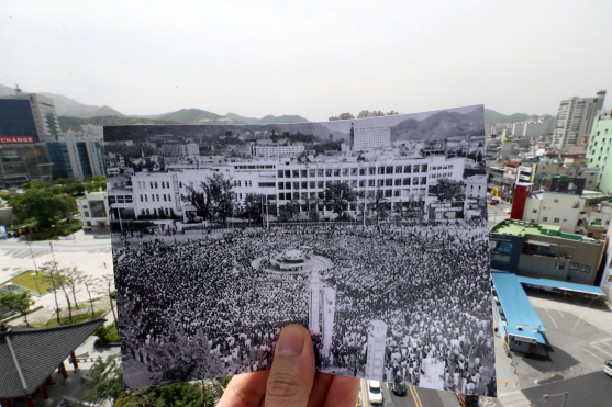 광주의 옛 전남도청 앞 광장에서 1980년 5월 민주화운동 당시 민주성회를 기록한 사진을 들고 지난 14일 촬영한 사진.   /광주=연합뉴스