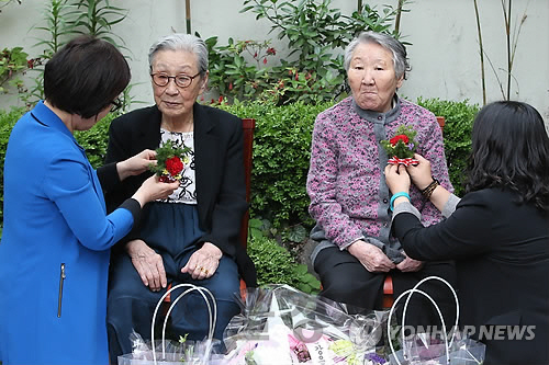 2015년 5월8일 어버이날을 맞아 서울 마포구 연남동 ‘평화의 우리집’에서 열린 위안부 피해 할머니 위로 행사에서 윤미향(맨 오른쪽) 정대협 상임대표와 이미경(맨 왼쪽) 새정치민주연합(현 더불어민주당) 의원이 김복동(왼쪽에서 두번째) 할머니와 길원옥(왼쪽에서 세번째) 할머니에게 카네이션을 달아주고 있다. /연합뉴스