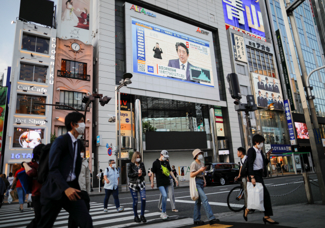 아베 신조 일본 총리의 신종 코로나바이러스 감염증(코로나19) 대응 관련 기자회견 모습이 14일 도쿄 신주쿠의 한 빌딩 건물에 설치된 대형 스크린을 통해 생중계되고 있다. /도쿄=로이터연합뉴스