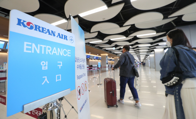 지난 17일 서울 강서구 김포공항 국내선청사에 위치한 대한항공 체크인카운터 앞에서 마스크를 쓴 승객이 걸어가고 있다./연합뉴스