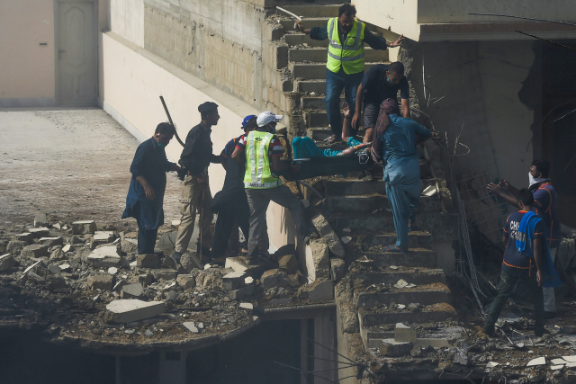 22ㅇ딜(현지시간) 파키스탄 카라치의 주택가에서 발생한 여객기 추락 사고로 인한 부상자들을 구조대원들이 대피시키고 있다. /카라치=AFP연합뉴스