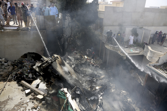 22일(현지시간) 소방대원들이 파키스탄 카라치에서 발생한 여객기 추락사고로 인한 화재를 집압하려 하고 있다. /카라치=AP연합뉴스