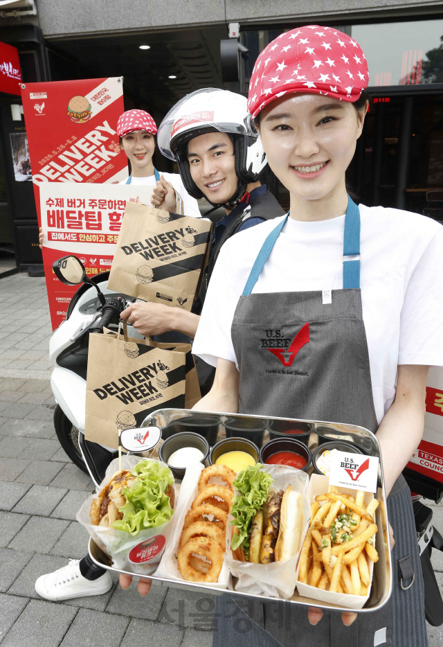 미국육류수출협회가 26일 서울 강서구 바스버거 마곡점에서 주최한 ‘딜리버리 위크(Delivery Week) 버거편’ 행사에서 홍보 모델이 배달팁이 할인된 버거 제품을 선보이고 있다. 이번 행사는 수제버거 12개 브랜드 29곳 매장이 참여하며 행사기간 내 제휴 배달앱으로 수제버거를 구매 시 배달팁 2,000원이 할인된다. 미국육류수출협회는 배달 요청이 많아지는 레스토랑에 도움을 주고 수제버거 고객들에게 할인 혜택을 선사하고자 이번 행사를 기획했다./미국육류수출협회 제공