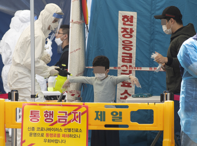 서울 강서구 보건소 선별진료소를 찾은 어린이가 26일 부모님과 함께 신종 코로나바이러스 감염증(코로나19) 검사를 받고 있다./연합뉴스