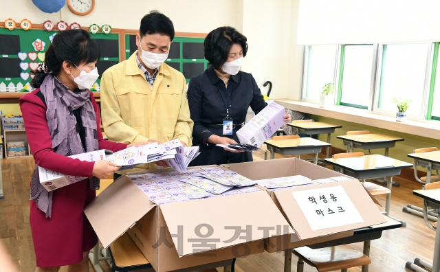 전국 유치원생과 초등 1∼2학년, 중3, 고2 학생들의 등교 수업을 하루 앞둔 26일 오전 서울 양천구 계남초등학교 1학년 교실에서 류영순(오른쪽) 교장과 심재삼(가운데) 신정7동장이 양천구에서 제공 받은 마스크를 살펴보고 있다. 양천구는 재난관리기금으로 구매한 마스크 49만장을 관내 103개 교육기관 학생 5만8,000여명에게 제공했다./오승현기자 2020.05.26