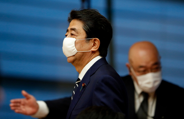 아베 신조(왼쪽) 일본 총리가 25일 도쿄 총리관저의 기자회견장에 들어서고 있다. 아베 총리는 이날 기자회견에서 코로나19 확산으로 선포한 긴급사태를 48일 만에 도쿄를 포함해 전면 해제한다고 발표했다. /도쿄=AFP연합뉴스