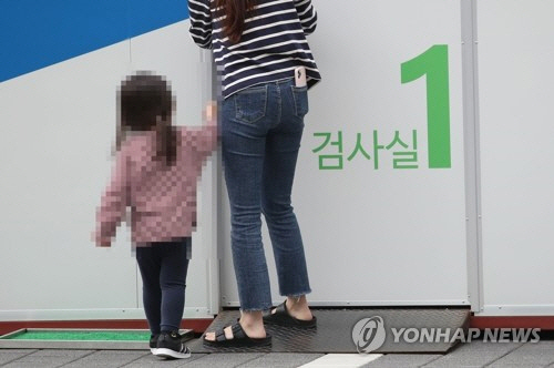 최근 서울 은평구보건소 선별진료소에서 한 어린이가 엄마와 함께 코로나19 검사를 받기 위해 검사실로 향하고 있다. /연합뉴스