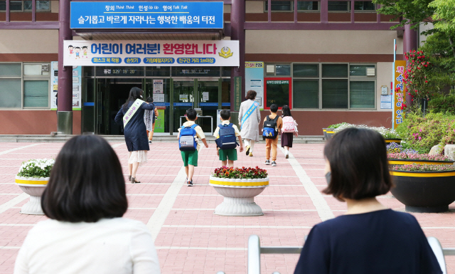 27일 경북 포항시 남구 포항제철지곡초등학교에서 1∼2학년 학생 등교 수업 첫날을 맞아 자녀가 학교에 들어가는 모습을 어머니가 지켜보고 있다. /포항=연합뉴스