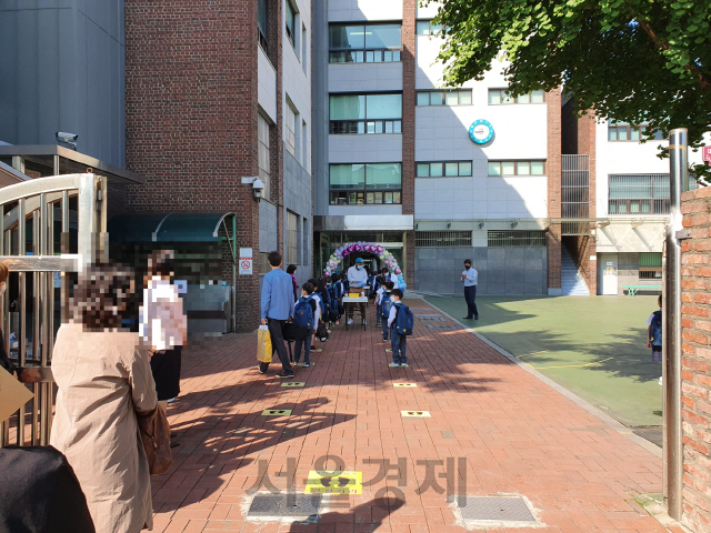 2차 개학이 이뤄진 27일 오전 서울 성북구 대광초등학교에서 등교한 학생들이 방역지침 준수를 위해 줄 지어 서있다. 정문 밖에는 기다리는 아이들을 바라보는 학부모들이 자리를 뜨지 못하고 있다./심기문기자