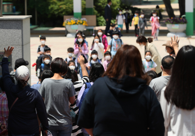 지난 27일 오전 서울시내 한 초등학교에서 학부모들이 하교하는 아이들을 향해 손을 흔들고 있다. /연합뉴스