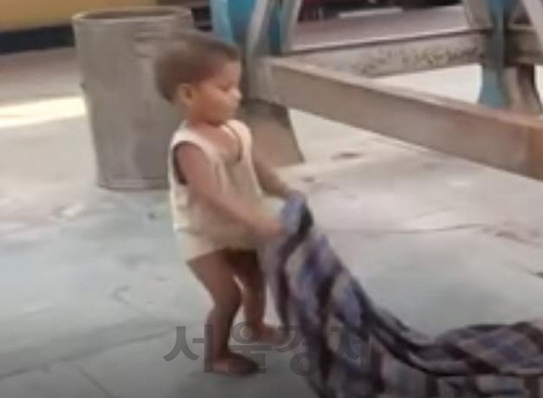 담요를 흔들어 엄마를 깨우려는 인도 기차역의 한 아기./SNS 영상 캡처