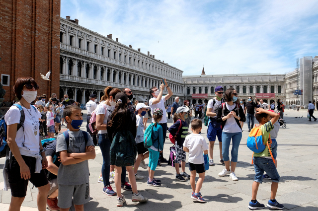이탈리아를 찾은 관광객들이 24일(현지시간) 마스크를 쓴 채 명소인 베네치아 산마르코 광장을 거닐고 있다. 베네치아 관광업계는 코로나19 사태에 따른 봉쇄조치로 큰 피해를 봤다. /베네치아=로이터연합뉴스