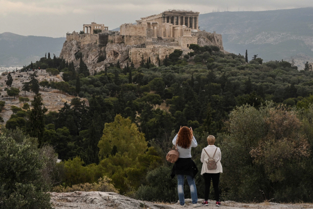 그리스 정부가 한국을 포함한 29개국 관광객의 입국을 허용하기로 한 가운데 두 명의 내국인 관광객이 29일(현지시간) 아테네의 아크로폴리스를 바라보고 있다./AFP연합뉴스