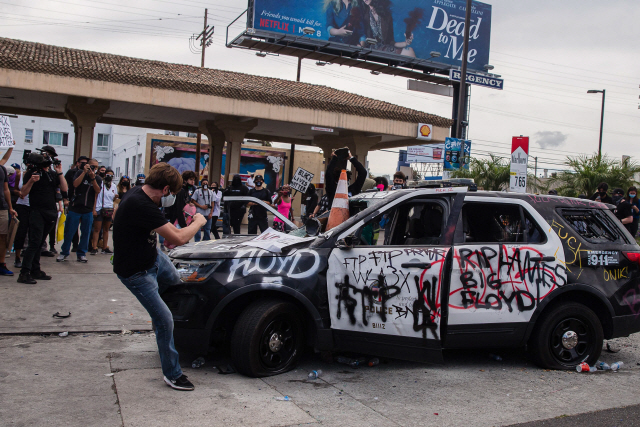 미국에서 흑인 남성이 경찰관의 체포 과정에서 숨진 데 대해 항의하는 시위가 갈수록 확산하는 가운데 30일(현지시간) 로스앤젤레스에서 한 시위자가 경찰차를 발로 차고 있다.  /AFP연합뉴스