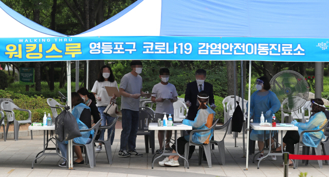 31일 오후 서울 여의도 자매근린공원에 마련된 코로나19 워킹스루 방식 선별진료소에서 시민들이 검사를 받고 있다./연합뉴스
