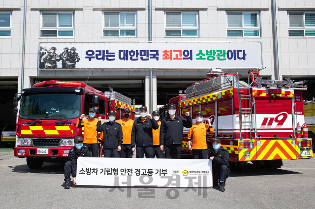 캐딜락이 기립형 안전 경고등세트를 기부한 청주서부소방서 소방관들이 차량 앞에서 사진 촬영을 하고 있다. /사진제공=캐딜락