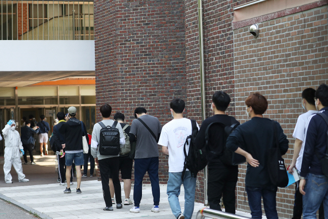 지난달 30일 서울시내의 한 학교에 마련된 순경 공채 필기시험장에 응시생들이 거리를 둔 채 줄을 서서 입장을 기다리고 있다. /연합뉴스