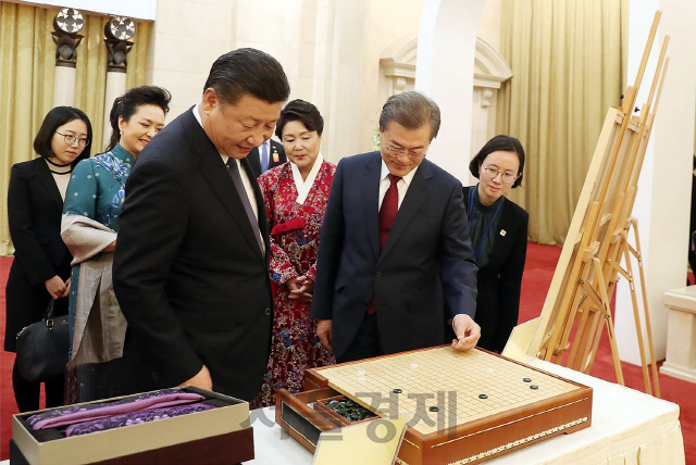 문재인 대통령이 지난 2017년 12월 14일 중국 방문 당시 국빈만찬에서 시진핑 중국 국가주석의 선물을 살펴보고 있다./사진=청와대 제공