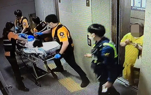 지난 1일 저녁 A군이 병원으로 옮겨지는 모습. 오른쪽 노란 옷이 계모 B씨./연합뉴스
