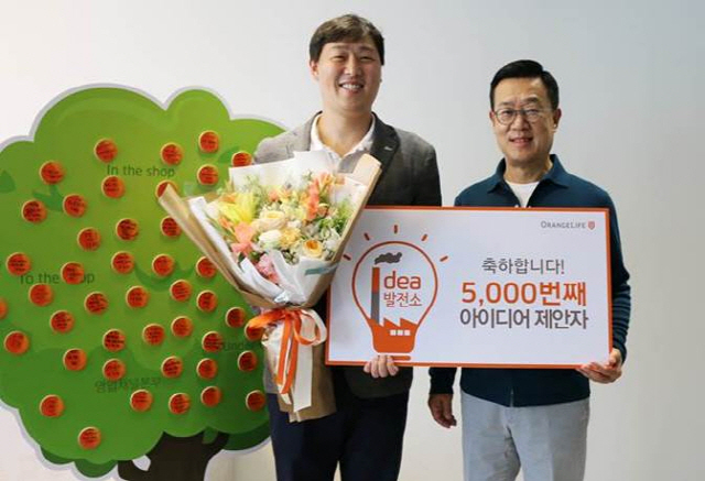 정문국(오른쪽) 오렌지라이프 사장이 4일 서울 중구 순화동 오렌지센터에서 5,000번째 아이디어를 제안한 이상학 오렌지라이프 고객전략챕터 과장에게 꽃다발을 전달하고 있다. /사진제공=오렌지라이프