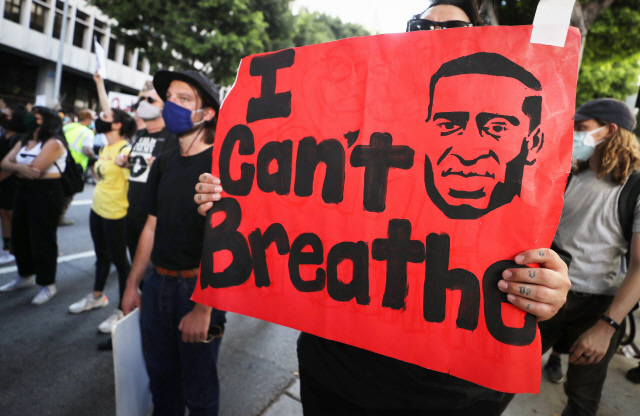 3월(현지시간) 백인 경찰의 과잉 진압으로 사망한 흑인 조지 플로이드를 추모하고 경찰에 항의하는 집회에서 한 참가자가 ‘숨을 쉴 수 없다’는 팻말을 들고있다./AFP연합뉴스