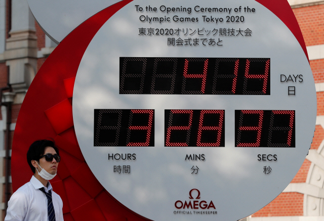 지난 4일 일본 도쿄의 2020 도쿄올림픽 카운트시계 앞을 마스크를 착용한 한 남성이 지나가고 있다./로이터연합뉴스