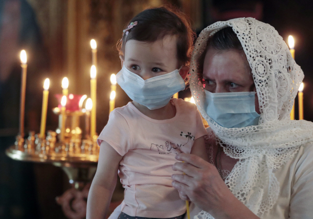 7일(현지시간) 러시아 모스크바의 한 교회에서 마스크를 한 여인이 아이와 함께 예배를 보고 있다./EPA연합뉴스